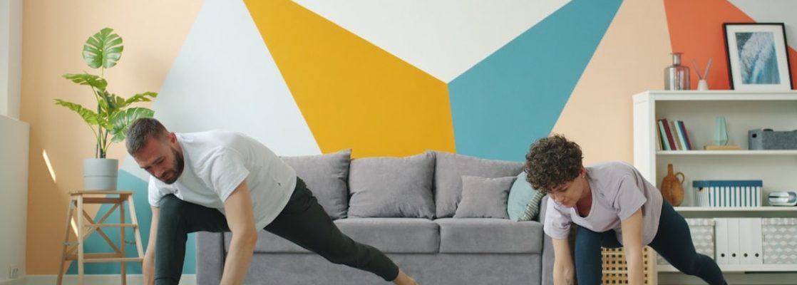 Woman and man are working out at home doing yoga together synchronously on mats caring for body health. Modern people, sports and apartment concept.